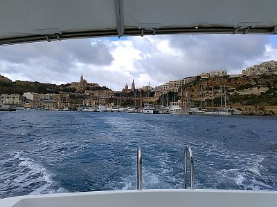 Lodička se stříškou se s námi vzdaluje od přístavu Mgar, míříme na Comino