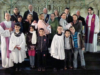 Londýnská farnost po křtu (dva kněží po stranách, jáhen uprostřed)