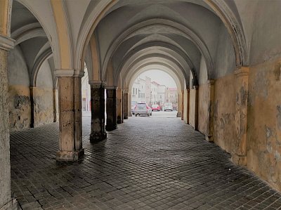 Tímto, v současnosti již nevzhledným podloubím se dá projít ke kostelu