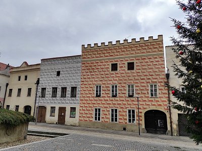 Některé fasády jsou zdobeny psaníčkovými sgrafity a zakončeny cimbuřím